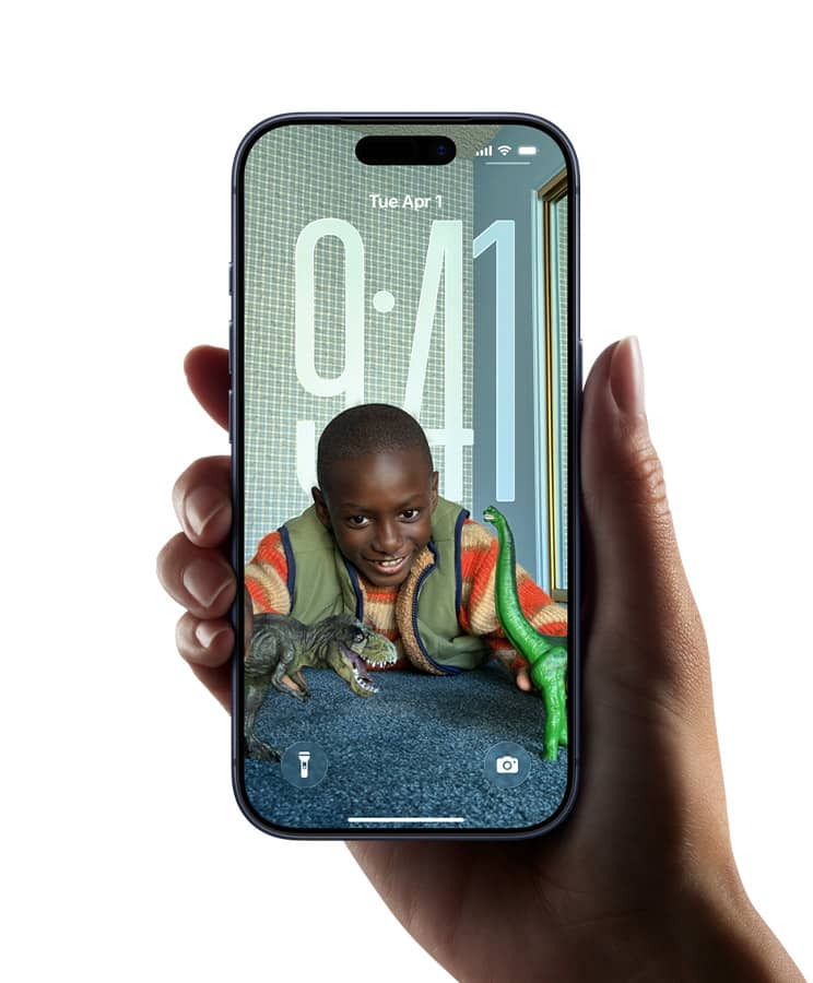 Hand holding an iPhone with a lock screen showing a smiling child playing with toy dinosaurs on a customizable iOS wallpaper.