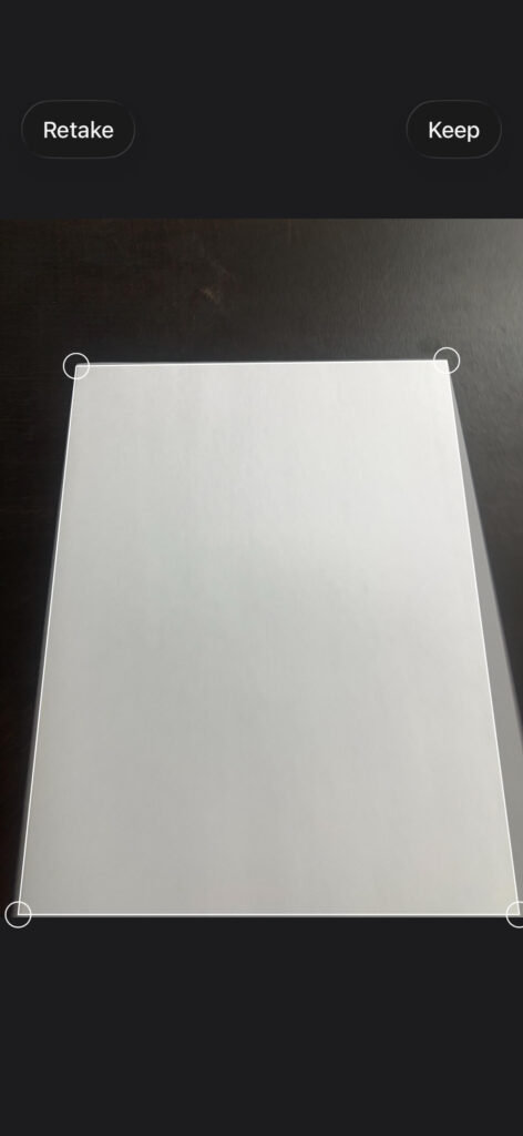 Document scanning preview in iPhone Notes showing crop corners and paper detection.